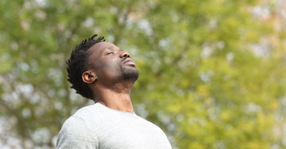 Man with eyes closed and head tilted back peacefully outdoors